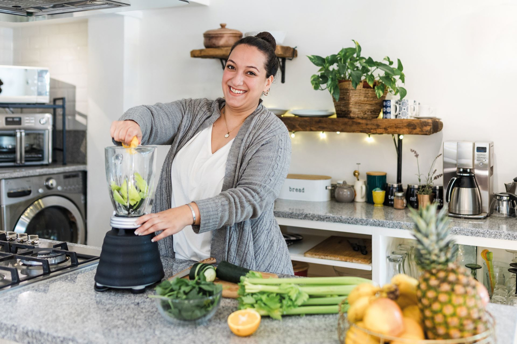 Frau mixed sich einen grünen Smoothy